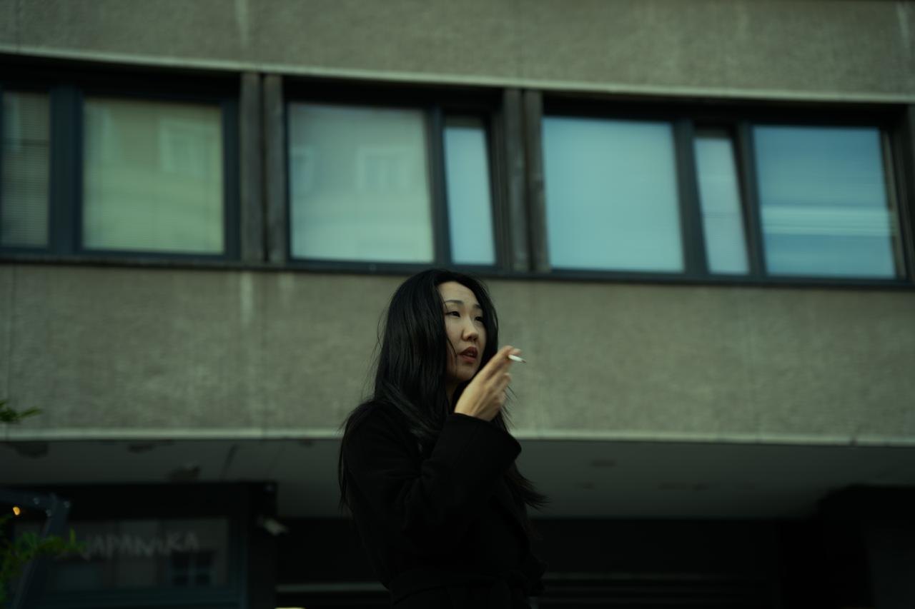 A woman smoking in front of a row of windows