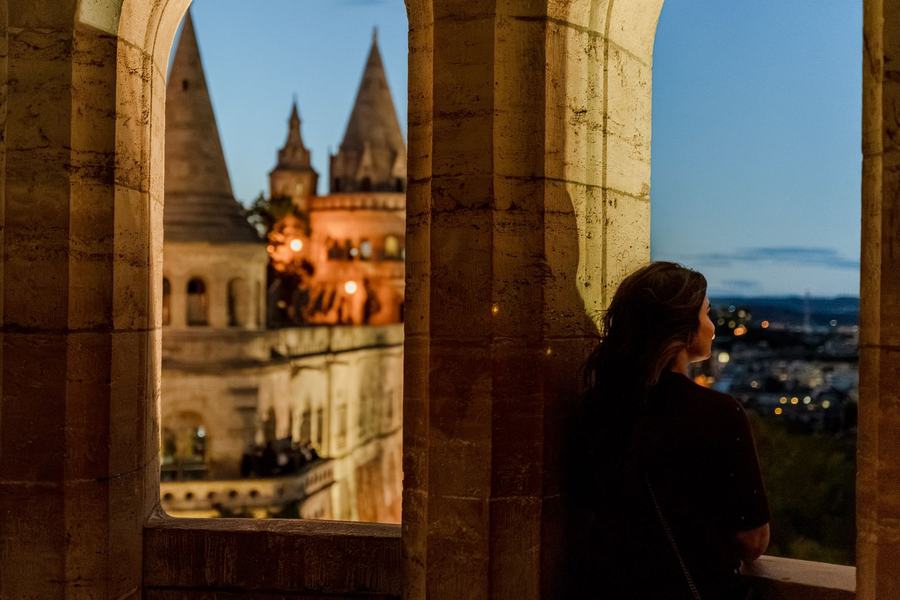 A woman looking out through an arch of Fisherman's Bastion at blue hour