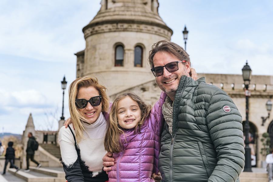 A family of three smiling together in front of Fisherman's Bastion