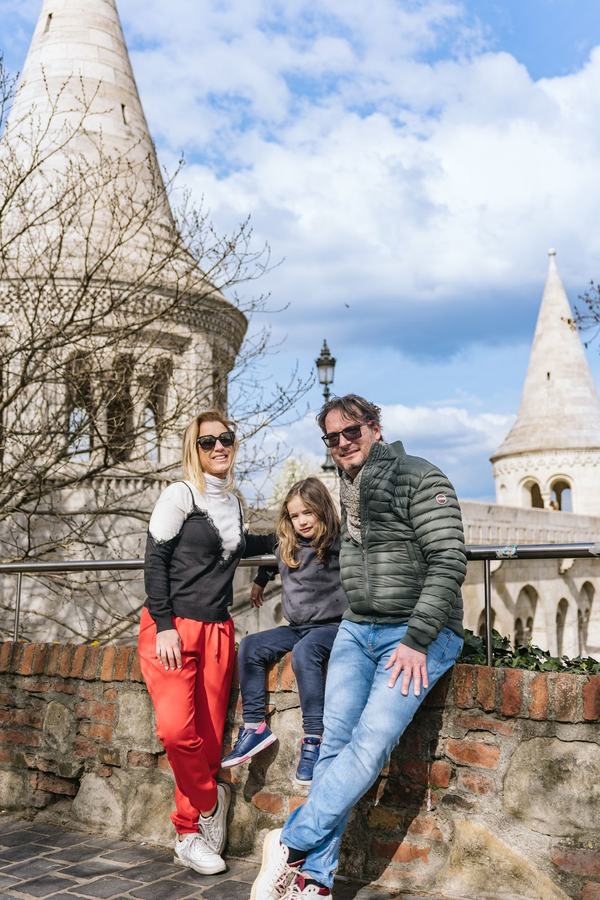 A family sitting on a brick wall below the white towers of Fisherman's Bastion