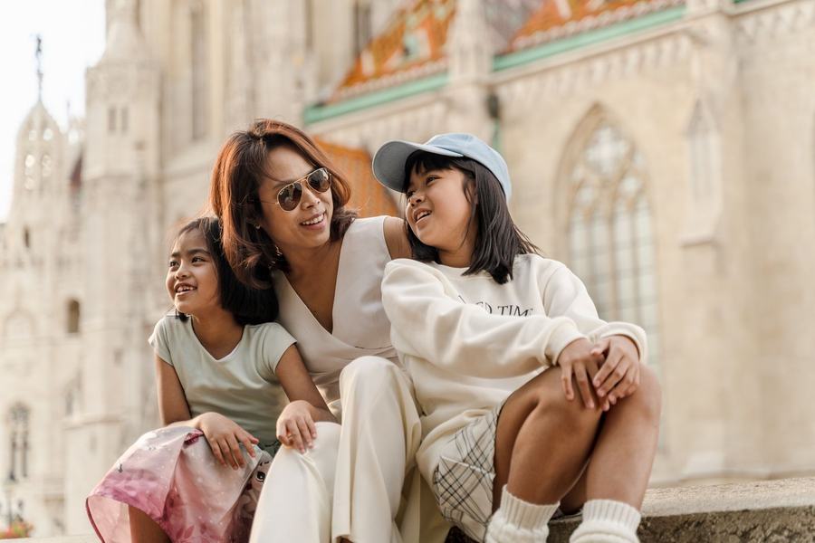 A mother and her two daughters laughing on the steps by Matthias Church