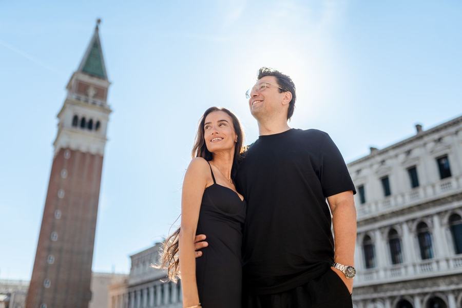 A smiling couple below the bell tower of St Mark's