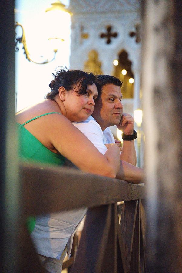 A couple leaning on a railing under a lantern at night in Venice