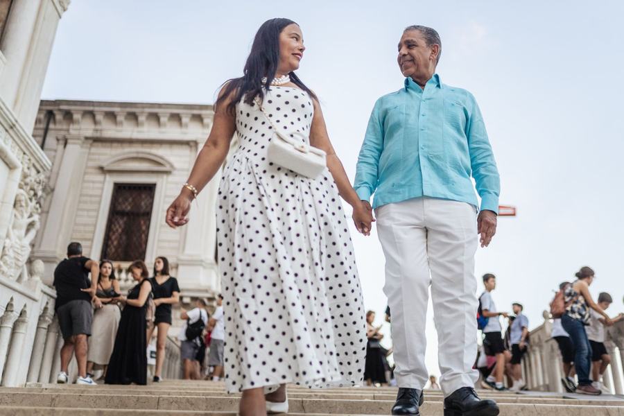 A couple walking hand in hand down white stone steps in Venice