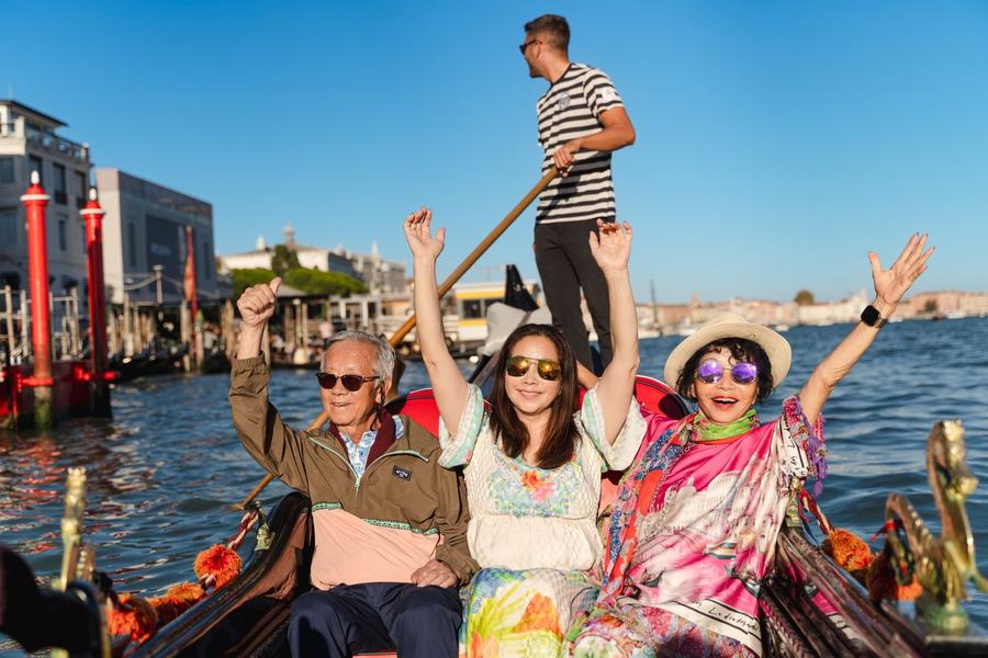 A family cheering with their arms up on a gondola on the lagoon