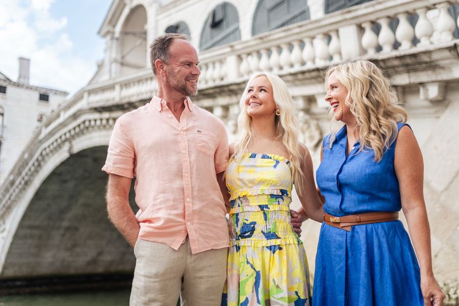 A daughter and her parents laughing in front of the Rialto Bridge