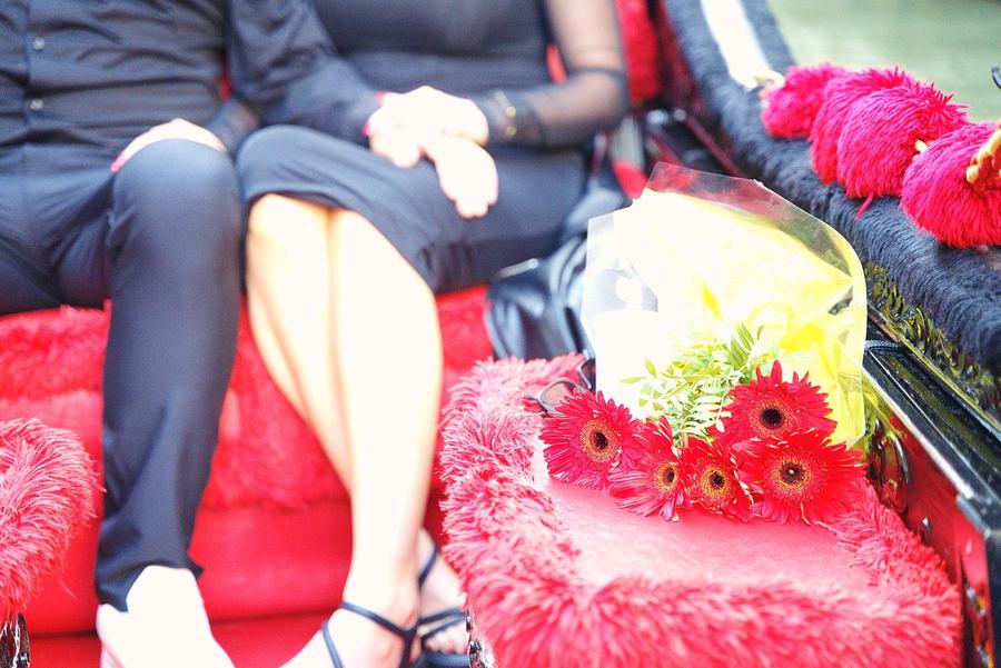 Red flowers on the red seat of a gondola, a couple's hands together