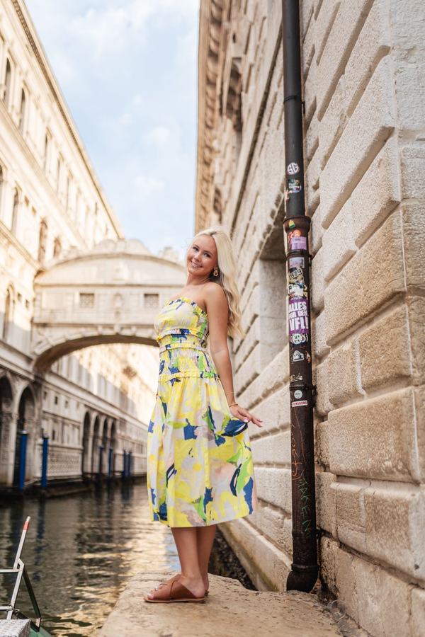 A woman in a yellow dress by the canal below the Bridge of Sighs